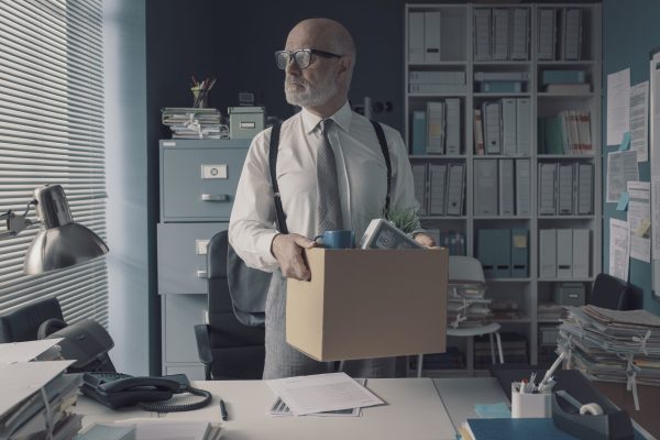 Corporate businessman packing his belongings and leaving the office, he has lost his job