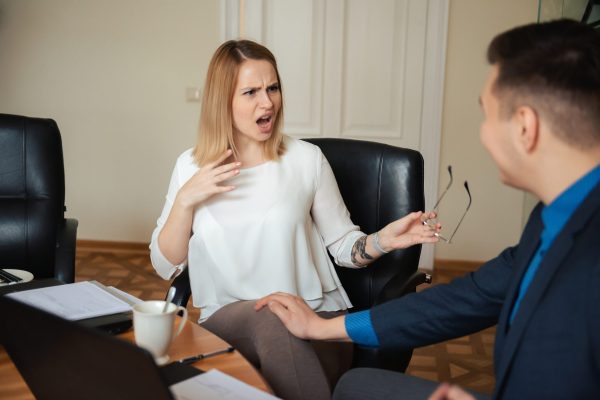 Businessman touching a young woman over his thighs at work