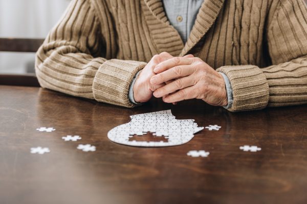 cropped view of retired man playing with puzzles on table