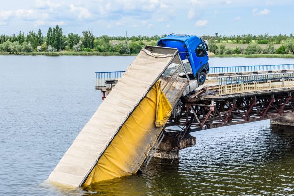 Destruction of bridge structures across the river with the collapse of sections into the water. Truck accident on destroyed bridge