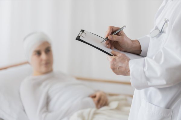 Close-up of senior doctor filling the documents about the patient after surgery