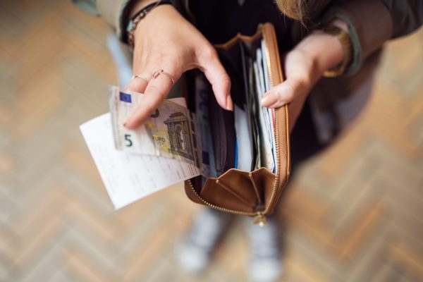 Woman holding open wallet with banknotes and receipts