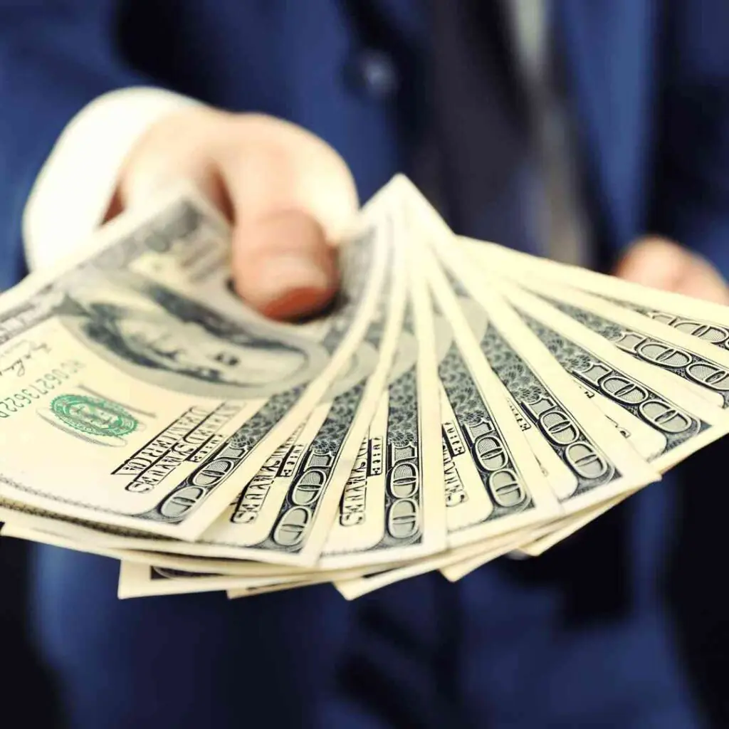 Hand holding cash to represent financial compensation.