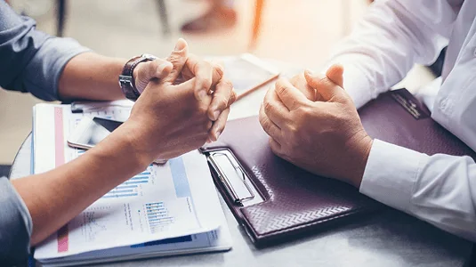 Close-up of hands reviewing paperwork during a consultation.