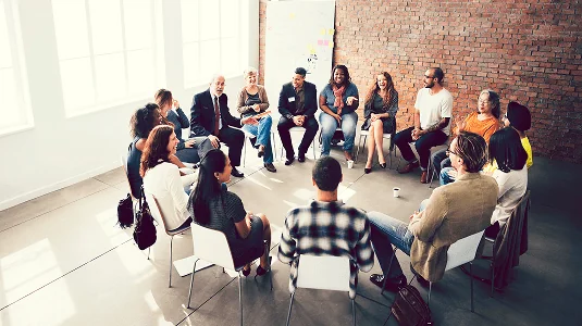 Group of professionals seated in a circle during a workplace discussion.