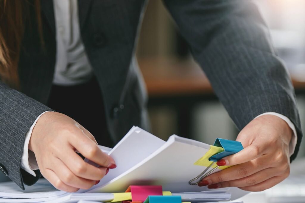 Person reviewing paperwork with sticky notes on a desk.